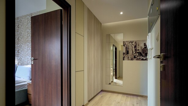 Une chambre d’hôtel avec un plancher en bois, un lit, une armoire et un miroir au mur.