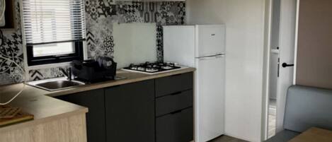 A compact kitchen with a gas stove, white refrigerator, and dark cabinets.