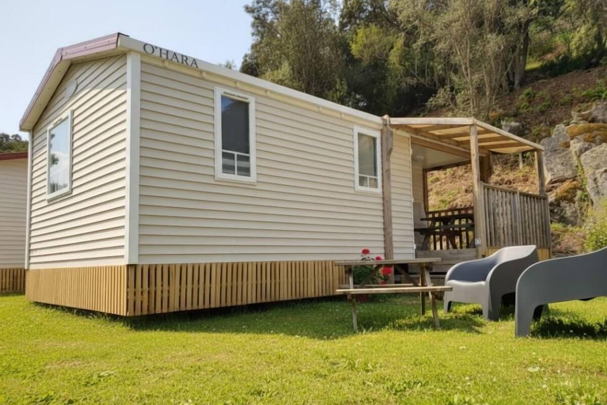 Une maison mobile de plain-pied dotée d’un porche couvert et d’une petite terrasse.