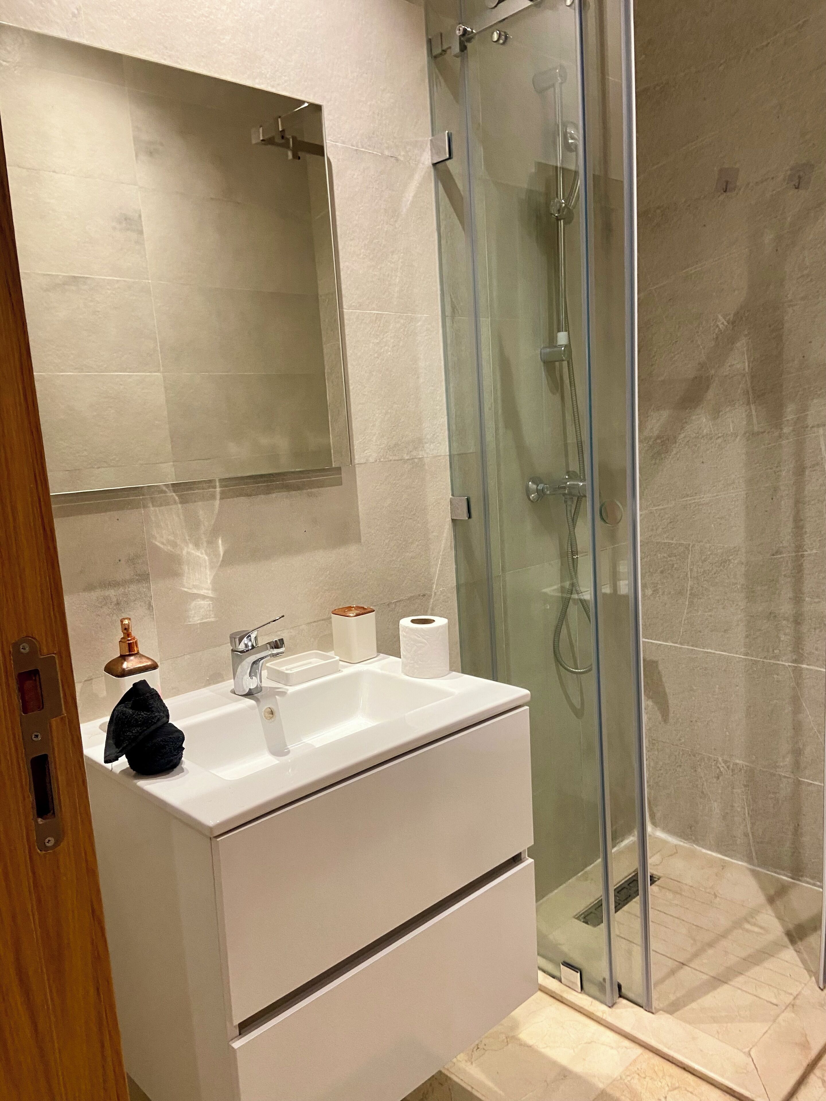 Ein modernes Badezimmer mit Waschbecken, Spiegel und Duschkabine aus Glas.