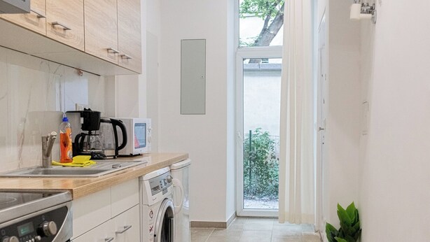 Una cocina moderna con lavadora, microondas y cafetera.