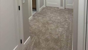 A hallway with carpeted floors, white walls, and three closed doors. - 1st Luxury Residential Elevator rooftop deck (Rochester)