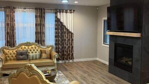 A living room with a sofa, a coffee table, a fireplace, and a television. - 1st Luxury Residential Elevator rooftop deck (Rochester)