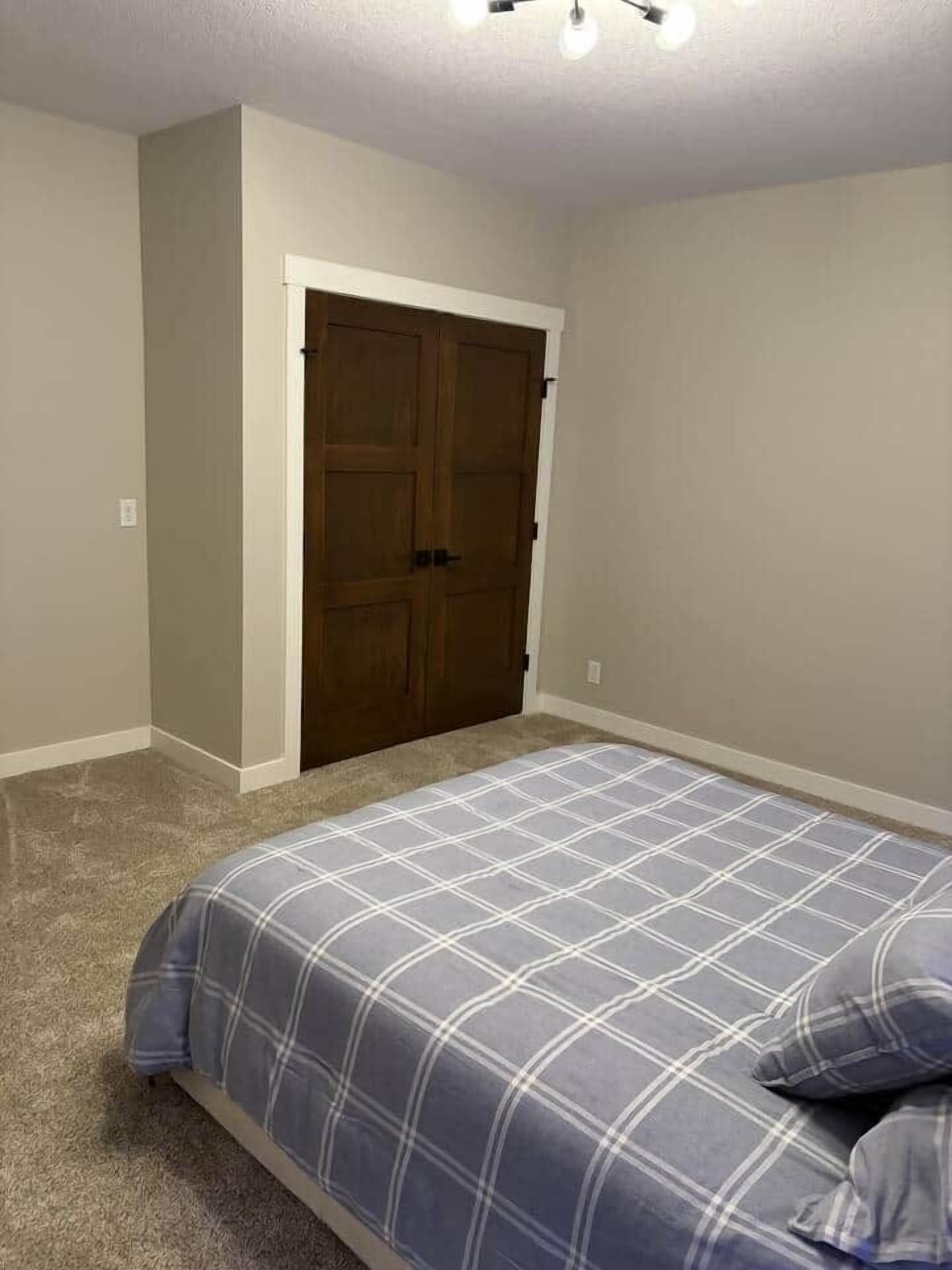 Une chambre à coucher avec un lit, une armoire et un sol recouvert de moquette.