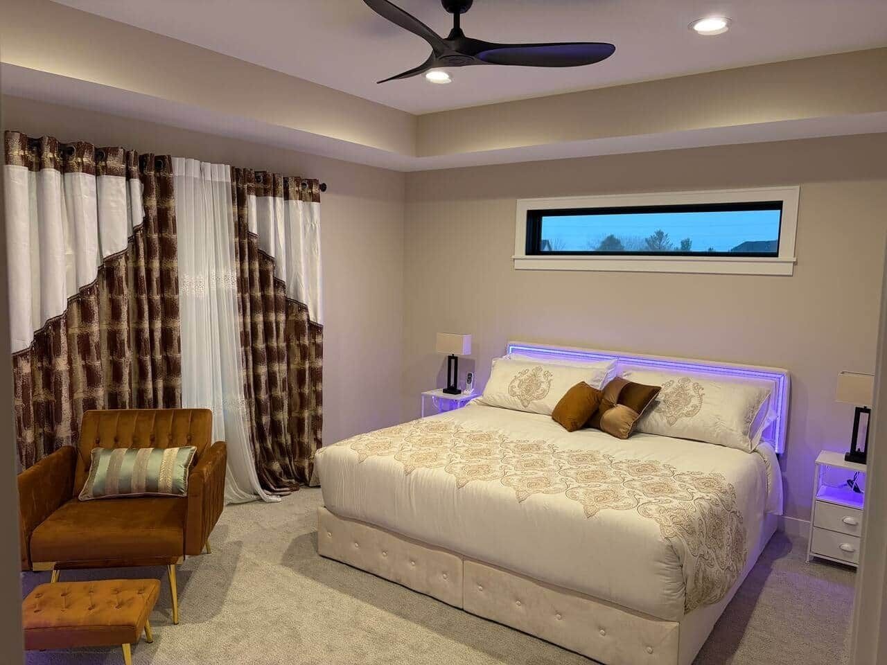 A bedroom with a large bed, a chair, a nightstand, and a window.