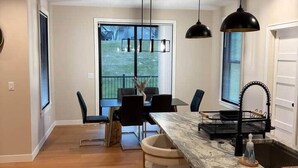 A modern kitchen with a marble countertop, black pendant lights, and a view of the outdoors. - Luxurious Sweet Escape stunning custom Home! (Rochester)