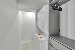 A modern laundry room with a white washing machine, a dryer, and a metal rack. - NEW house in Miami| Casa Calle 19 By Dream Vacation (Miami)