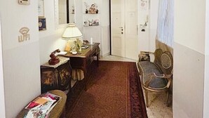 A narrow hallway with a wooden bench, a small table with a lamp, and a chair. - Ch Colosseum home (Rome)