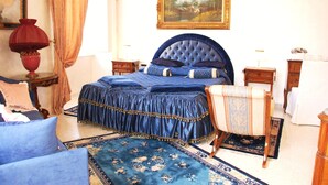 A bedroom with a large bed, a chair, a nightstand, a dresser, and a painting on the wall. - Ch Colosseum home (Rome)