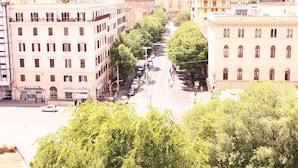 A street view with buildings, trees, and parked cars. - Ch Colosseum home (Rome)
