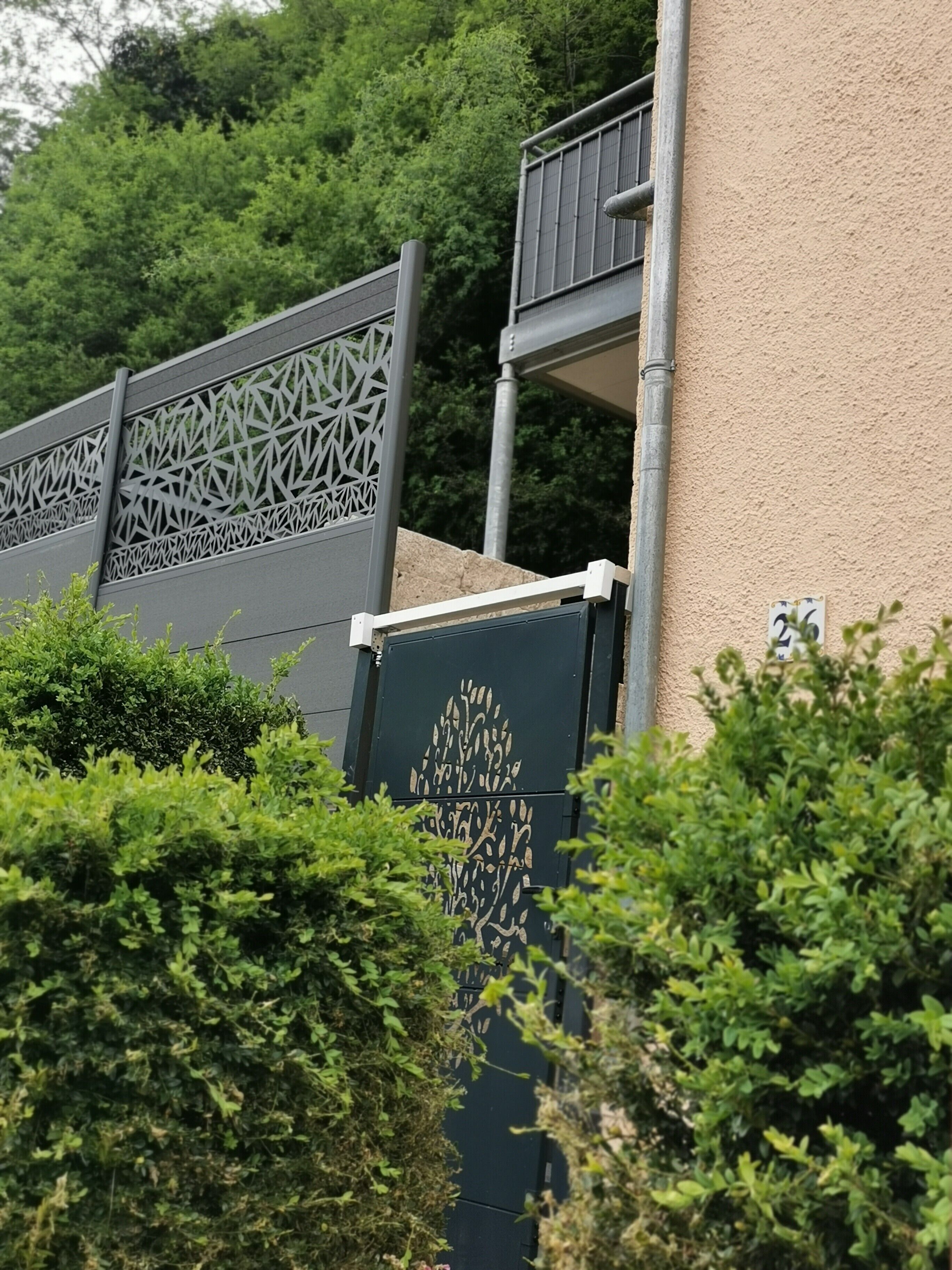 Un edificio con una facciata esterna strutturata, un cancello in metallo con motivi geometrici e un piccolo balcone.