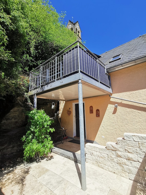 A building with a balcony, stone walls, and a clear blue sky.