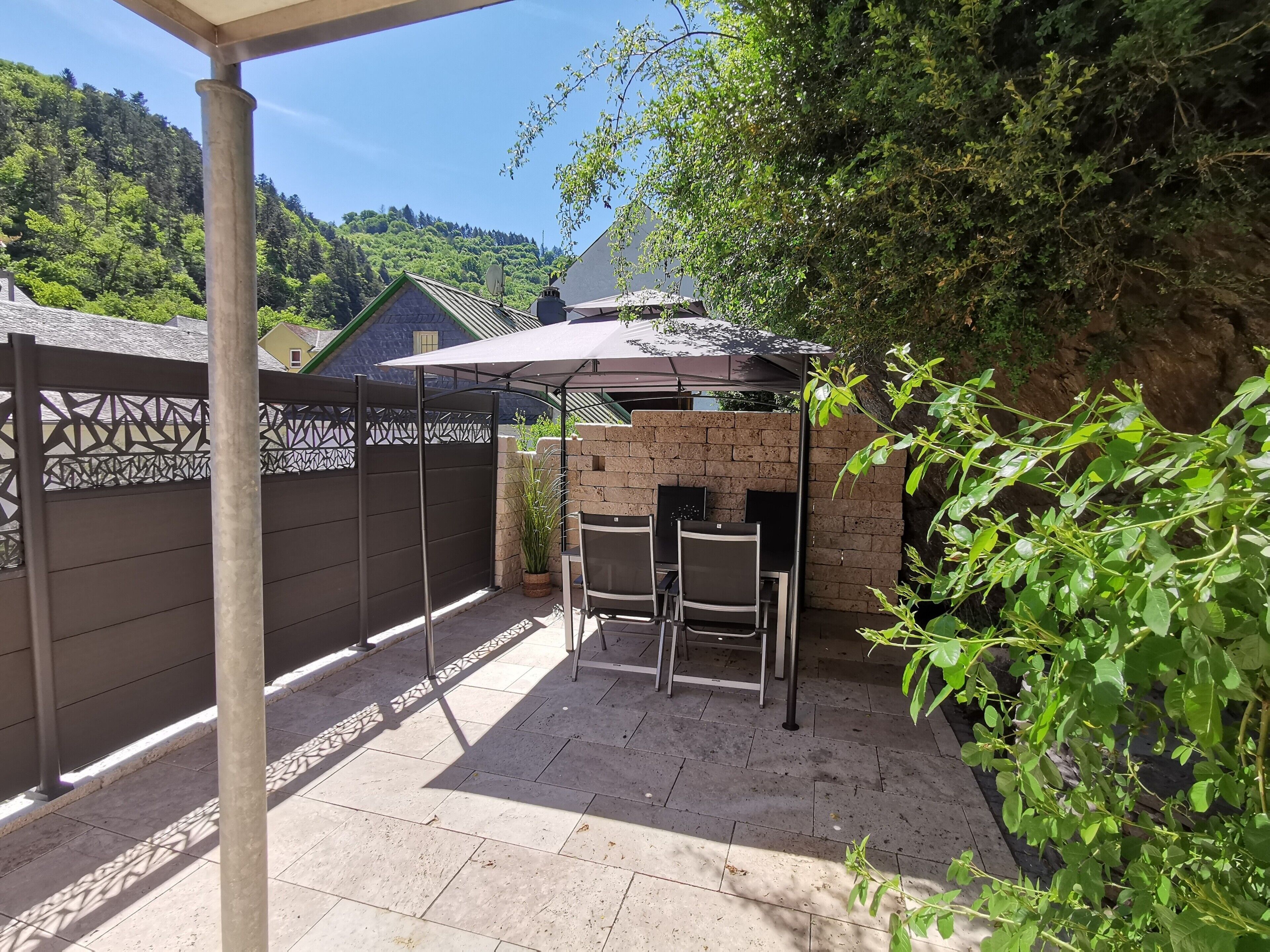 Un patio con una parrilla, sillas y una pérgola.