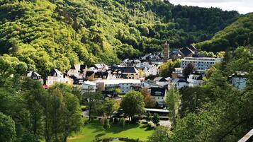 A town with historic buildings, a central square, and a hill with dense forest.