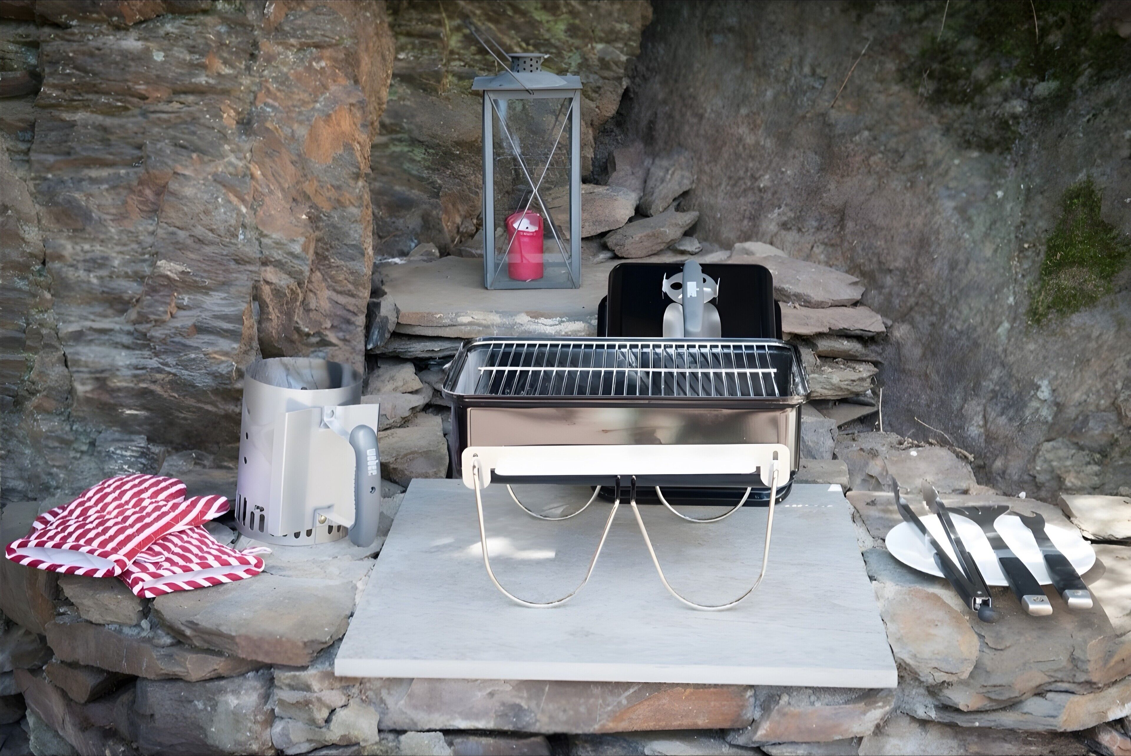 Eine Steinsäule mit Grill, Laterne und Metallbehälter.