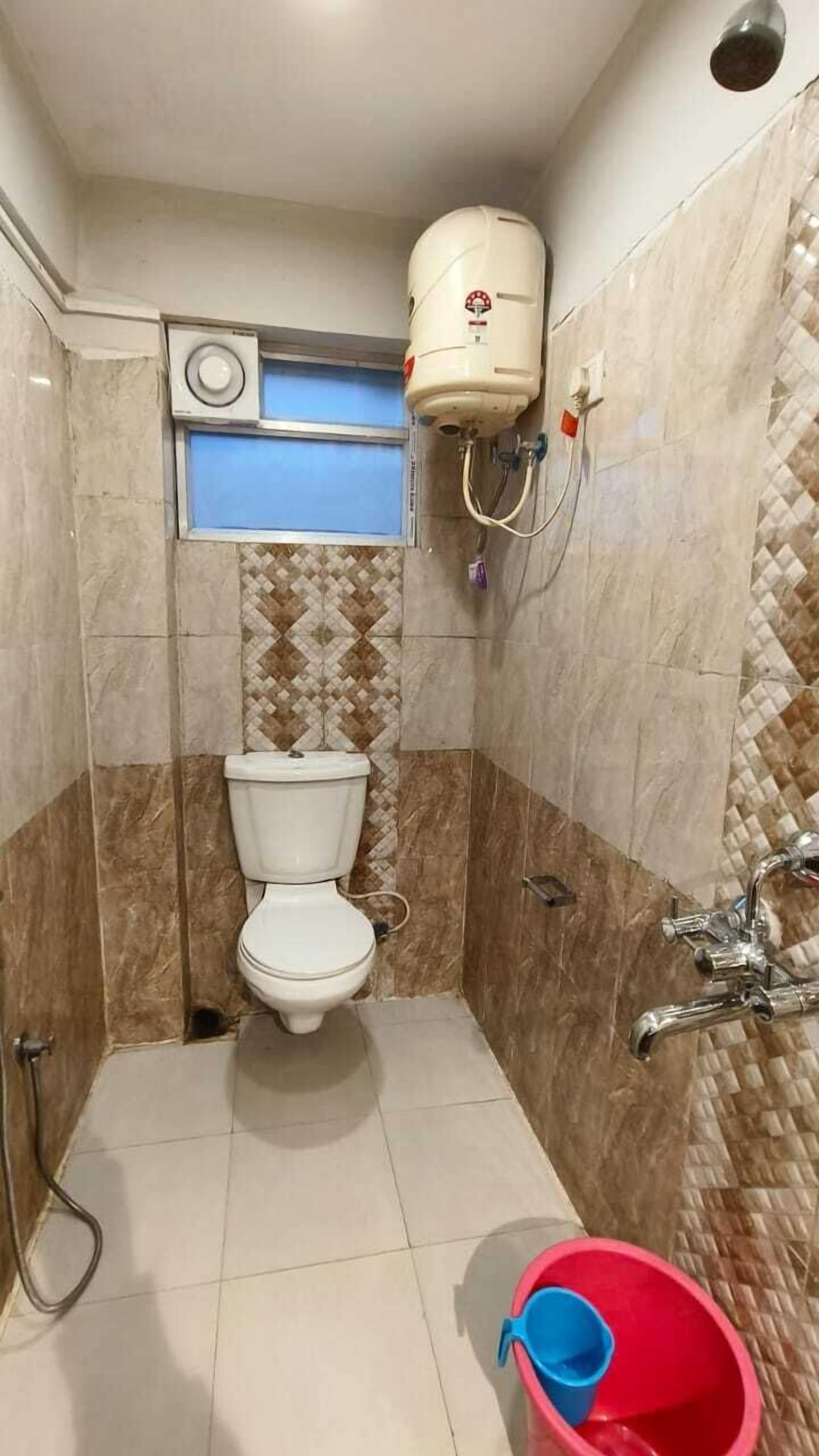 A small bathroom with a toilet, a shower, and a water heater mounted on the wall.