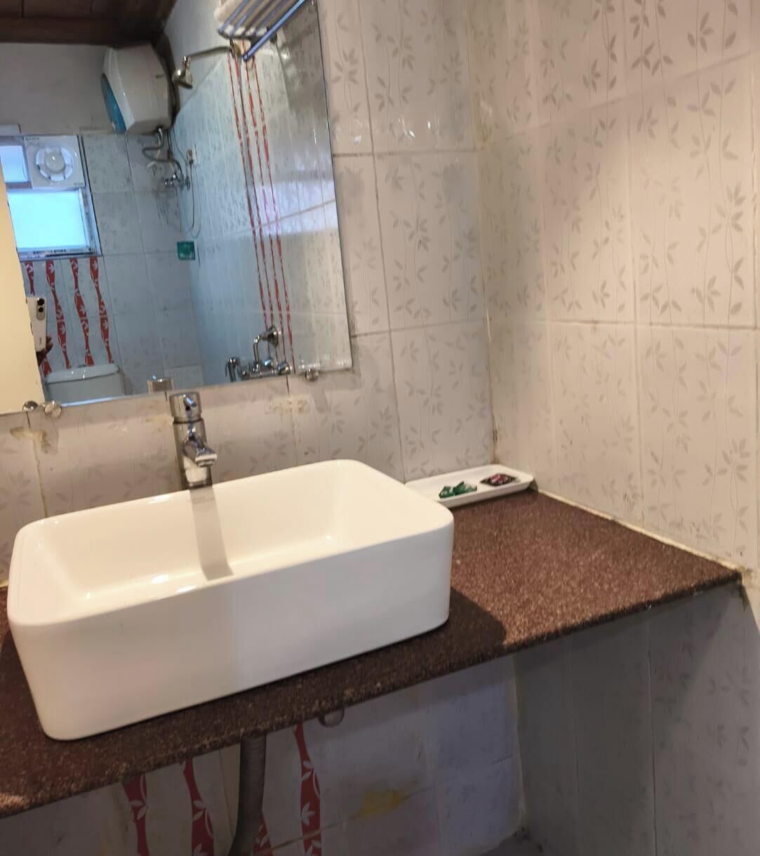 Een badkamer met een wit wastafelmeubel, een spiegel en een douche.
