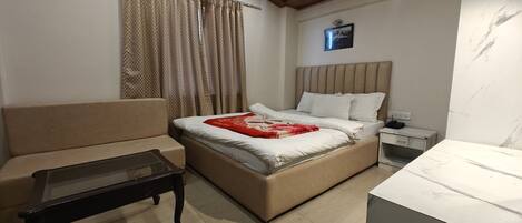 A bedroom with a bed, a sofa, a nightstand, and a small table.