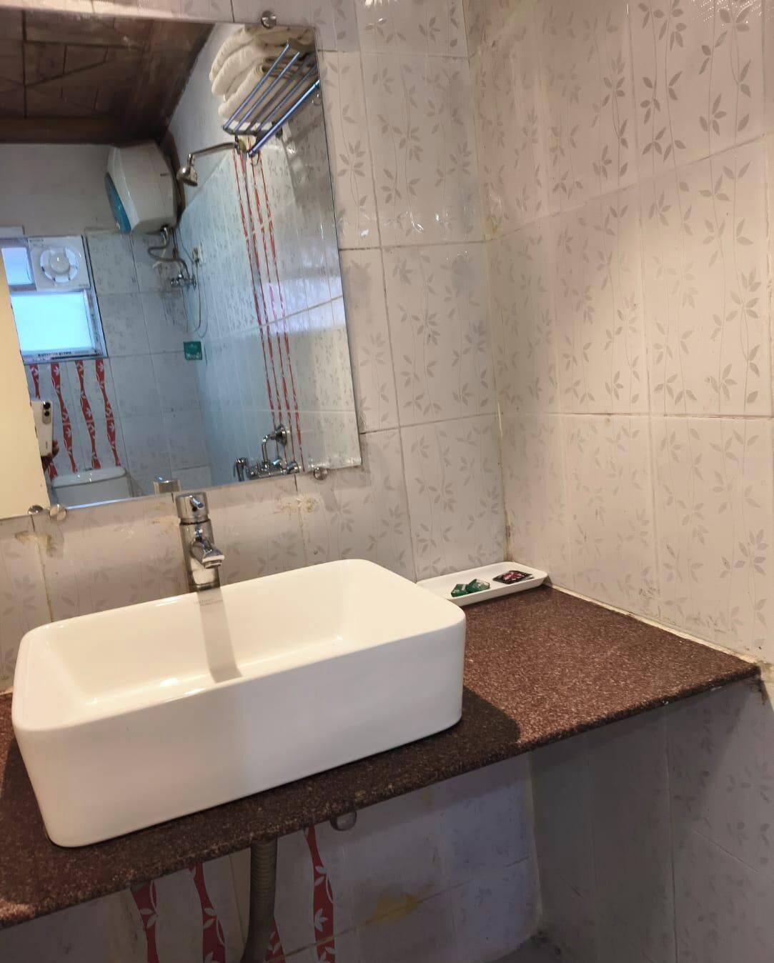 Une salle de bain avec un lavabo blanc, un miroir et un espace douche.