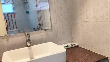 A bathroom with a white sink, a mirror, and a shower area.