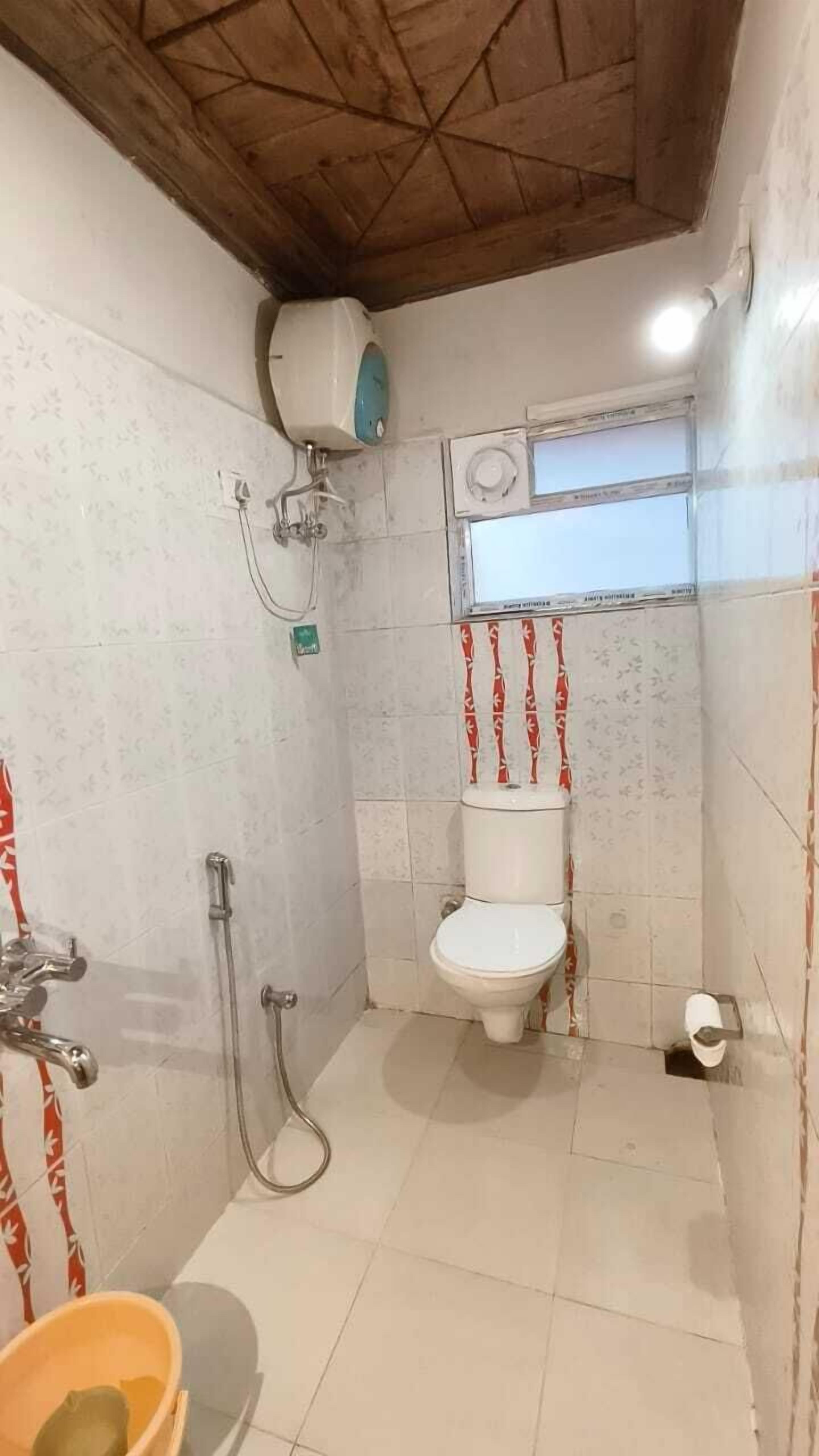 A small bathroom with a toilet, shower, and a window.