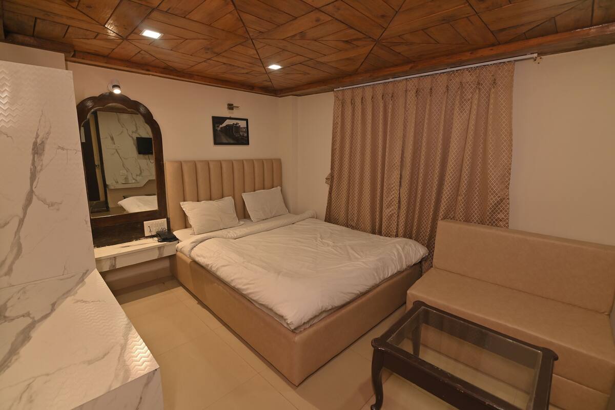 Een slaapkamer met een bed, een slaapbank, een nachtkastje, een spiegel en een wandlamp.