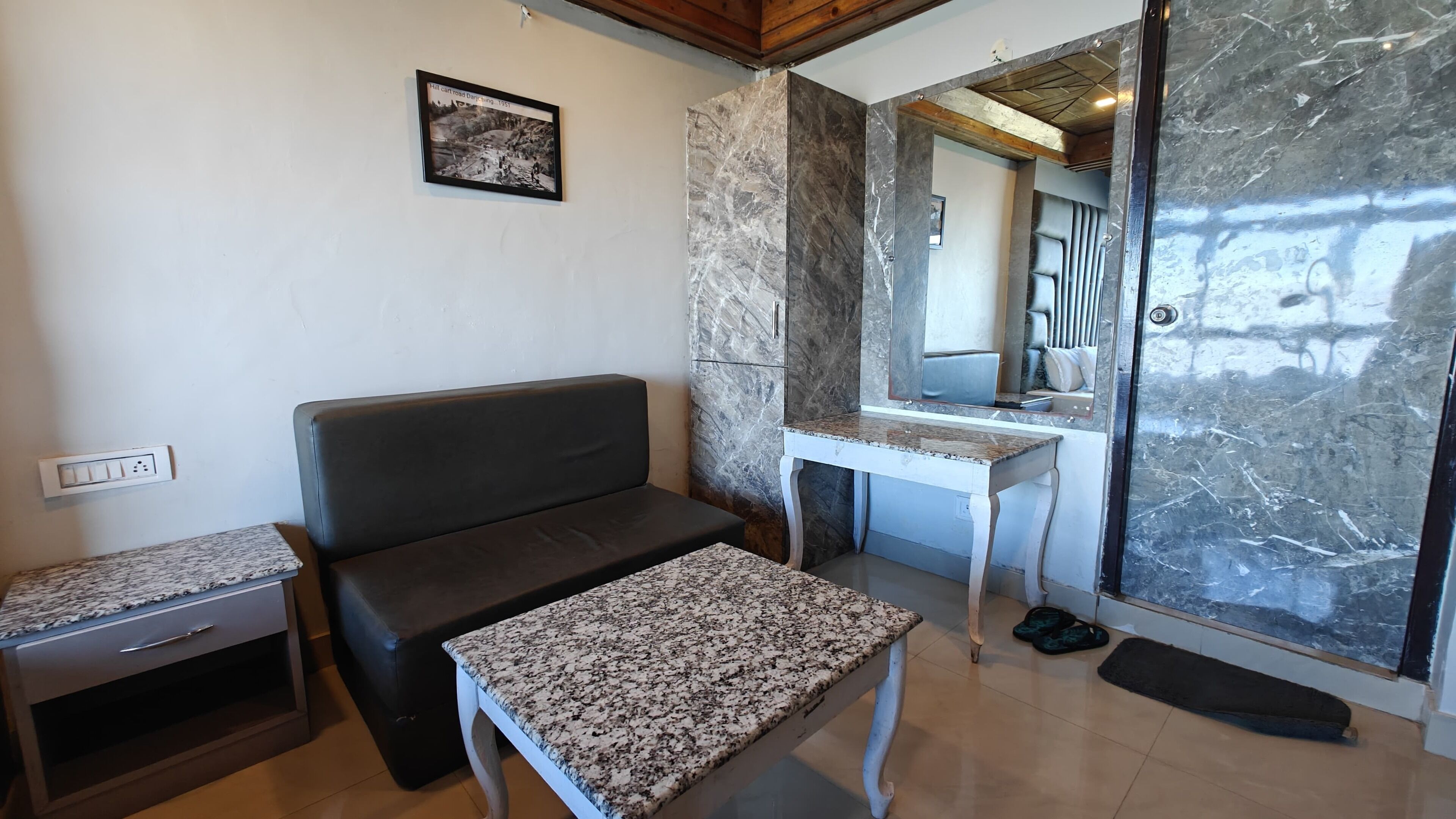 A modern living room with a dark sofa, a small table, and a marble wall.