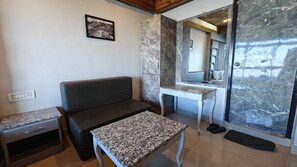 A modern living room with a dark sofa, a small table, and a marble wall. - Hotel Dreamland Darjeeling (Darjeeling)