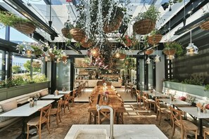 Ein Restaurant mit hohen Decken, hängenden Pflanzen und einer Bar.