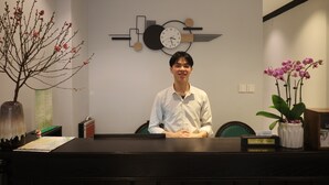 A reception desk with a clock, a vase with flowers, and a menu board. - Maya Central Hotel & Spa (Hanoi)