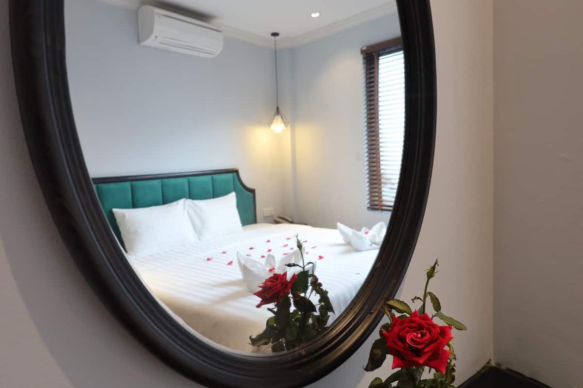 A neatly made bed with white linens, a teal headboard, and a bedside table with a lamp.