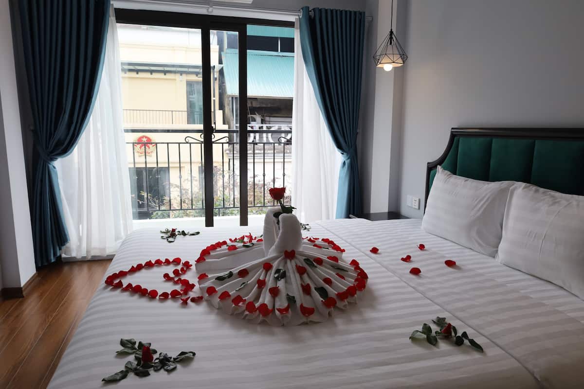 A hotel room with a bed, a balcony, and curtains.