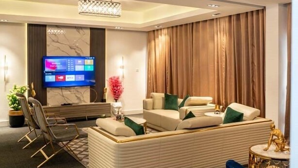 A modern living room with a flat-screen TV, comfortable seating, and a decorative light fixture. - Sujimoto luxury  (Lagos)