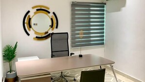 A conference room with a long table, chairs, a modern wall art piece, and a window with blinds. - Sujimoto luxury  (Lagos)