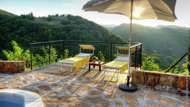 Eine Terrasse mit zwei Betten, einem Tisch, einer Flasche und einem Sonnenschirm.