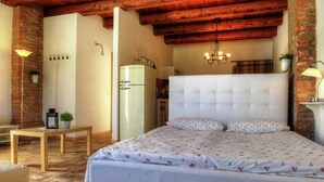 Ein Schlafzimmer mit einem Bett, einem Holztisch, einer Lampe und einer Backsteinwand.