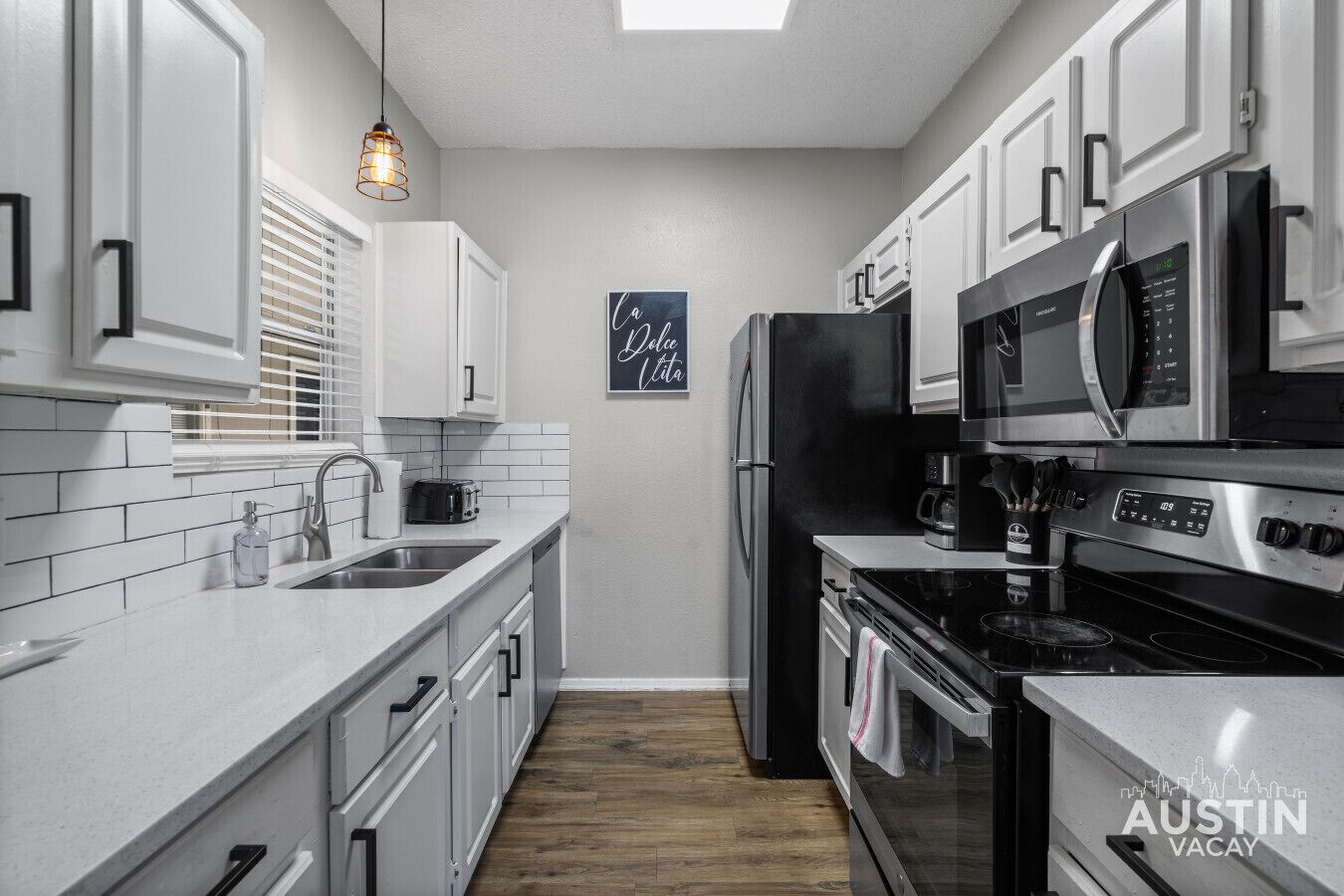 A modern kitchen with white cabinetry, stainless steel appliances, and a wooden floor.
