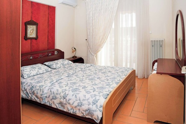 A bedroom with a bed, a nightstand, a mirror, and a radiator.