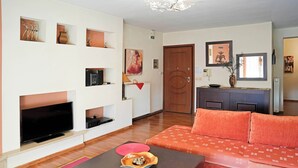 Een moderne woonkamer met een flatscreen televisie, een bank, een salontafel en een open haard.