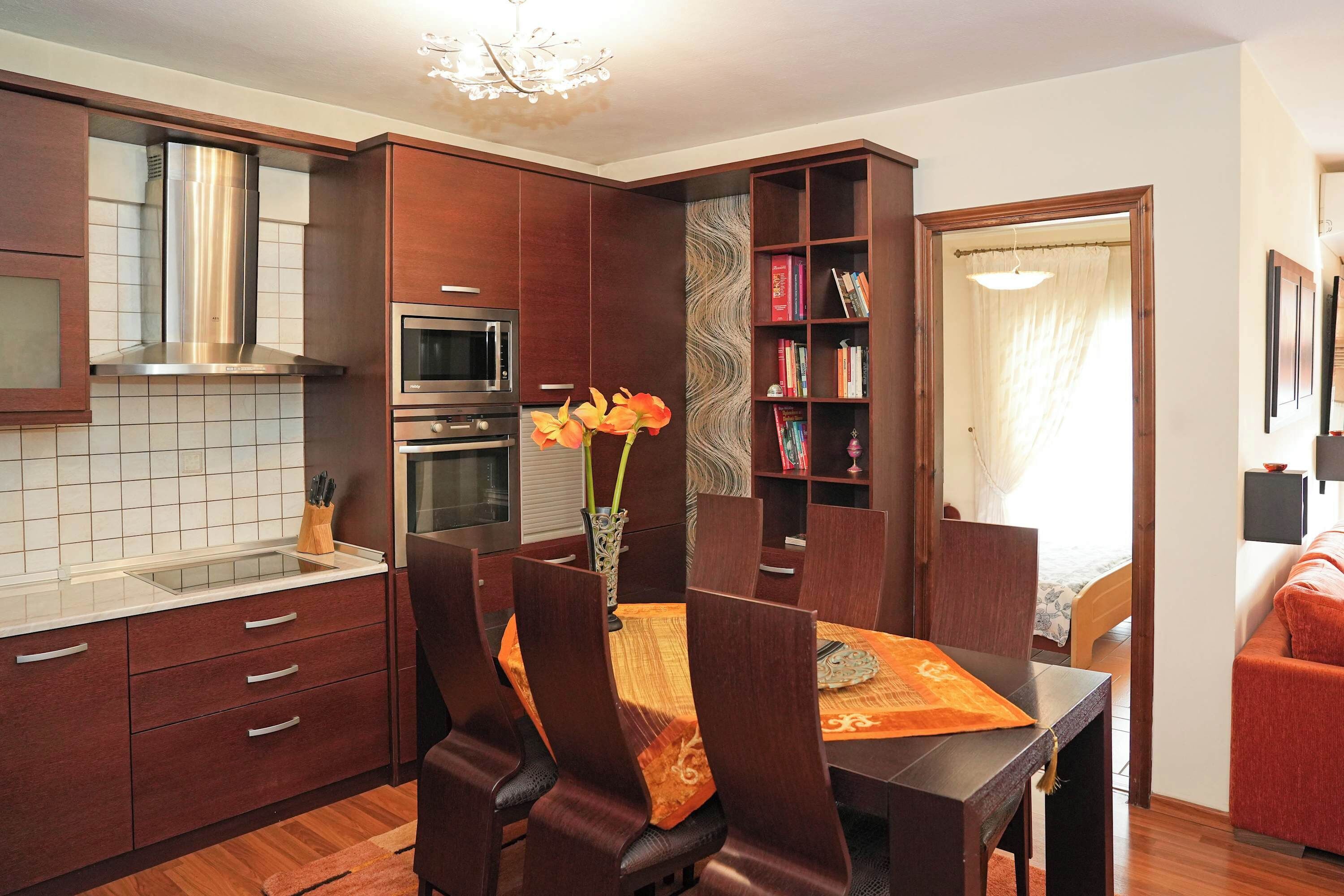 Una cucina moderna con mobili in legno, forno integrato e zona pranzo con tavolo e sedie.