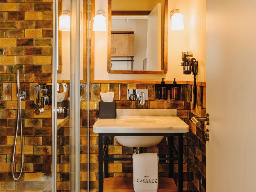 Un baño con cabina de ducha de vidrio, tocador de madera, un espejo grande y un perchero para toallas.