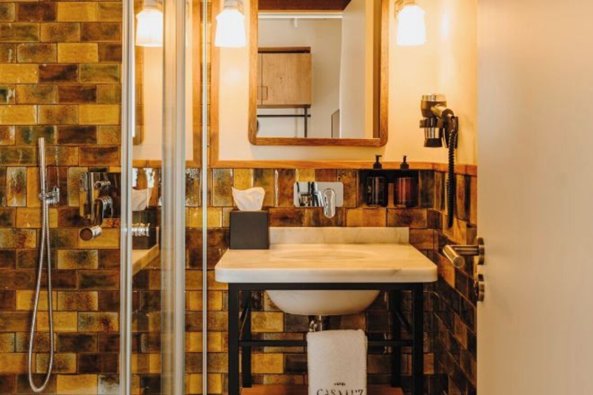 A bathroom with a glass shower enclosure, a sink with a towel, and a mirror.