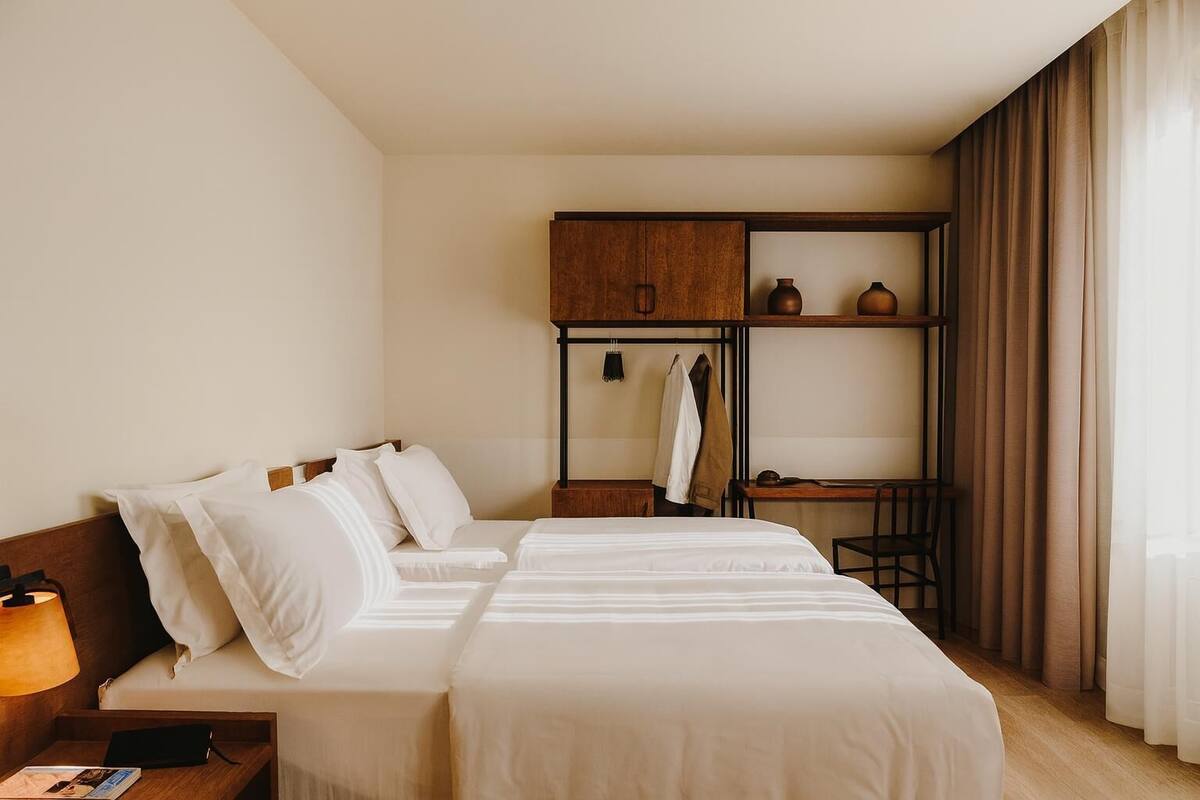 A hotel room with a bed, a desk, a wardrobe, and a chair.