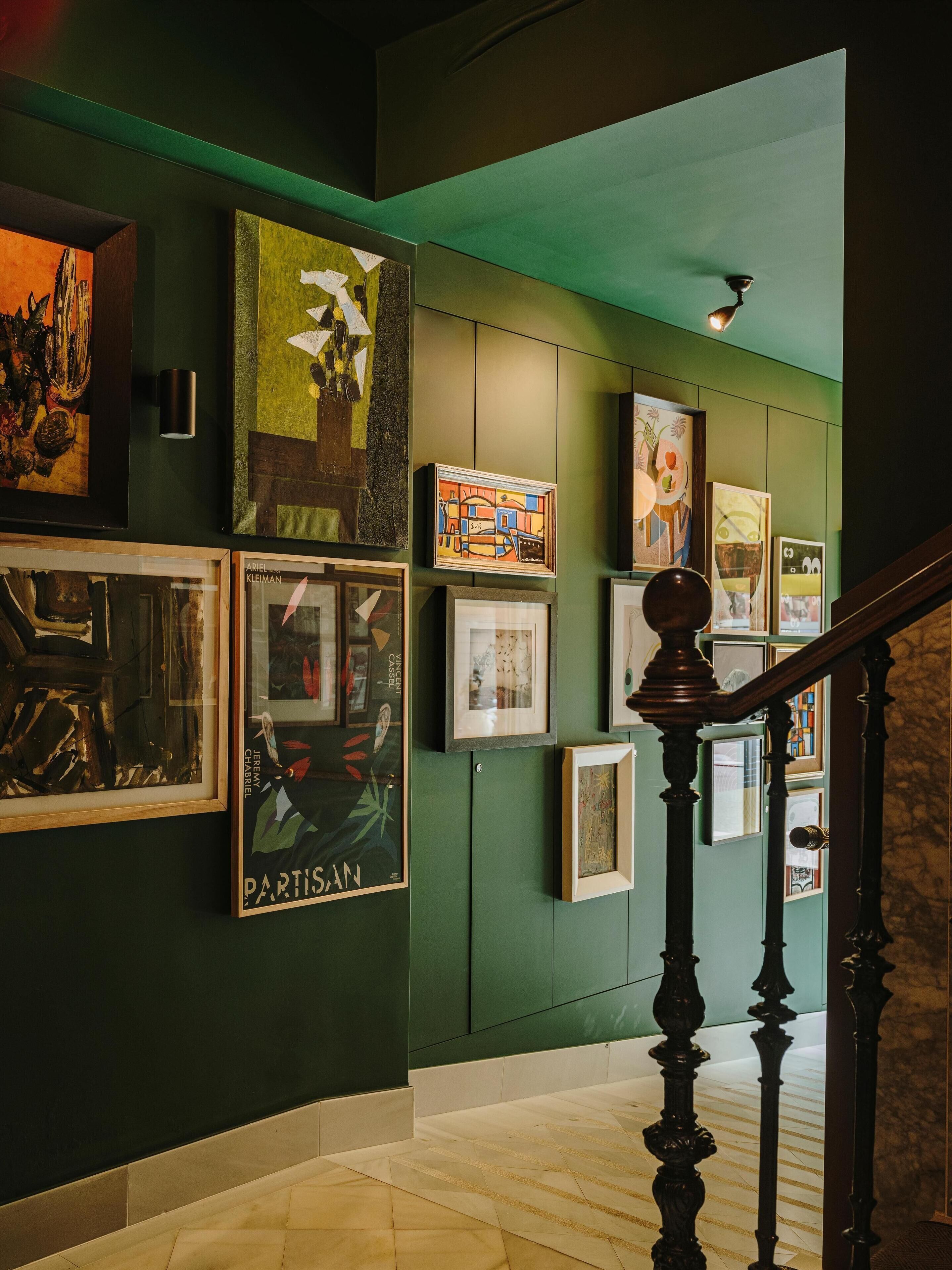 A hallway with green walls and a wooden staircase.
