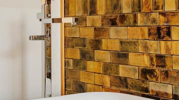 Un baño con una bañera blanca, un grifo de cromo y una pared de azulejos con diseño de ladrillo.
