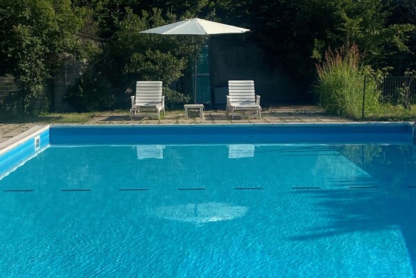 A swimming pool with two lounge chairs and a sun umbrella. - Il Dondolo near Bergamo with a summer pool (Mozzo)