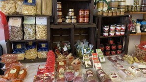 Diversos alimentos à venda, incluindo massa, enlatados e carnes embaladas, em uma loja.