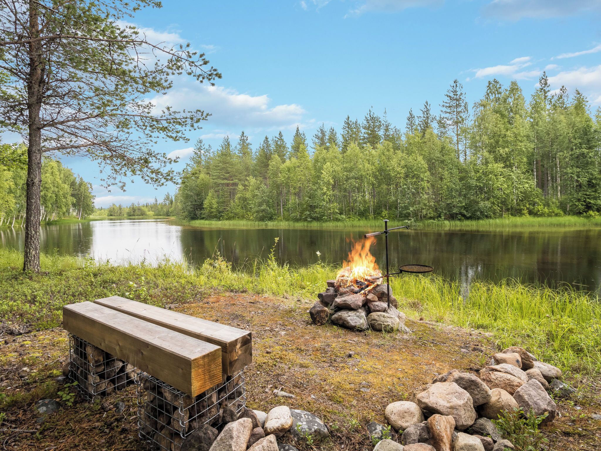 A lakeside campsite with a fire pit and a bench.