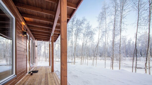 Una terraza de madera con vistas a un bosque nevado.