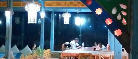 An outdoor dining area with tables and chairs, decorative elements, and hanging lights.